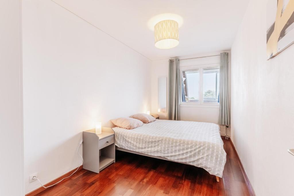 a white bedroom with a bed and a window at Gwenhen - Appartement vue mer in Courseulles-sur-Mer