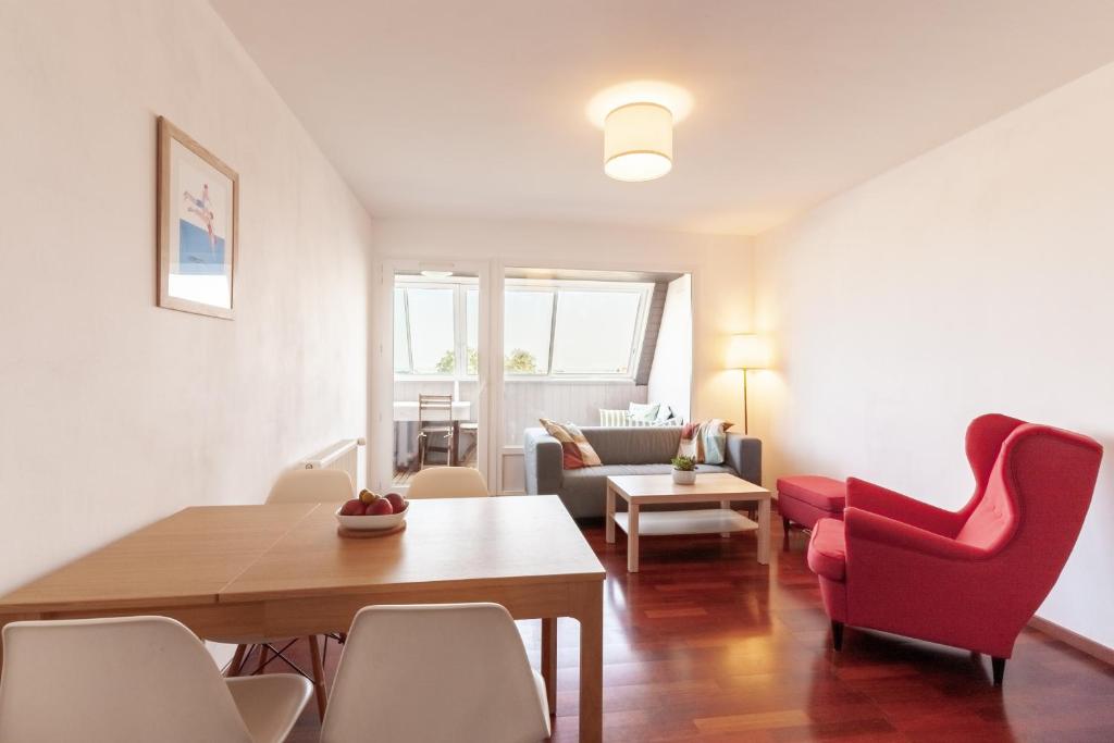 a living room with a table and red chairs at Gwenhen - Appartement vue mer in Courseulles-sur-Mer