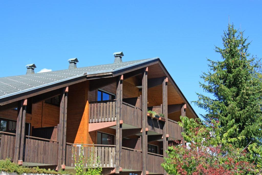 Cette grande maison en bois dispose d'un balcon et d'un arbre. dans l'établissement Azureva La Clusaz les Aravis, à La Clusaz