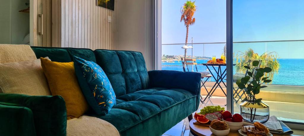 eine blaue Couch in einem Wohnzimmer mit Blick auf das Meer in der Unterkunft Phaedrus Living: Seaview Emerald Flat Lighthouse 48 in Paphos City