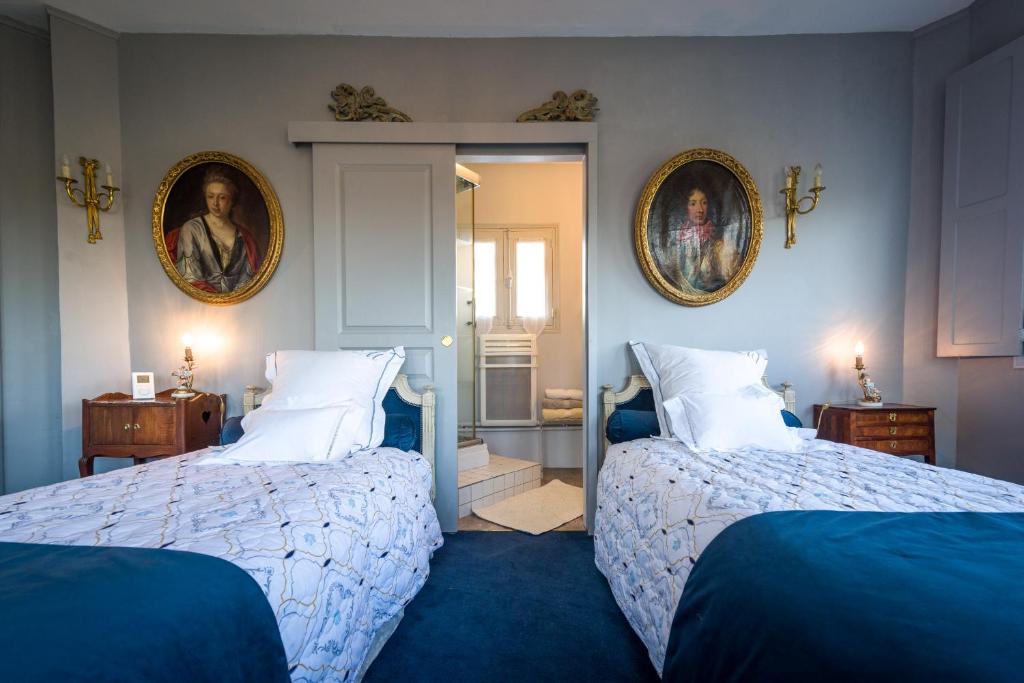 a bedroom with two beds and two portraits on the wall at Chambres d&#39;Hôtes Manoir de Montecler in Chènehutte-les-Tuffeaux