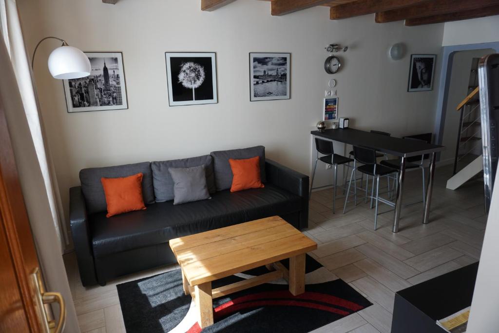 ein Wohnzimmer mit einem schwarzen Sofa und einem Tisch in der Unterkunft Duplex Rue Haute in Laneuveville-derrière-Foug