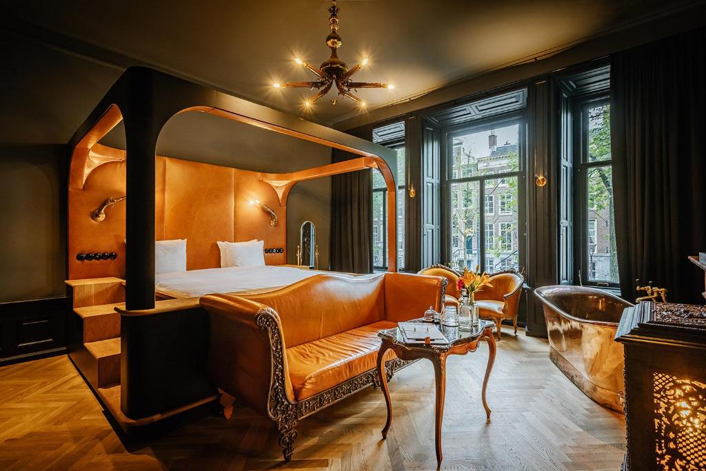 a hotel room with a bed and a couch and a table at Boutique Hotel The Noblemen in Amsterdam