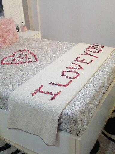 a bed with a white blanket with red writing on it at Appartement Fes très propre et calme in Fez