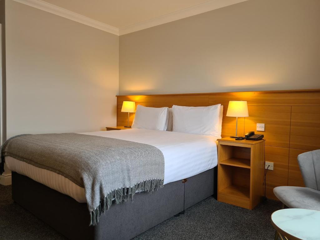 a hotel room with a large bed and a chair at Caisleain Oir Hotel in Annagry