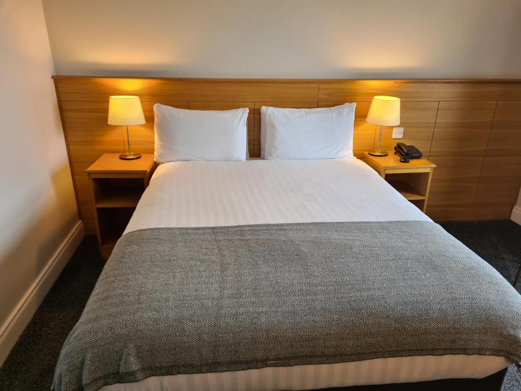 a bedroom with a large white bed with two lamps at Caisleain Oir Hotel in Annagry