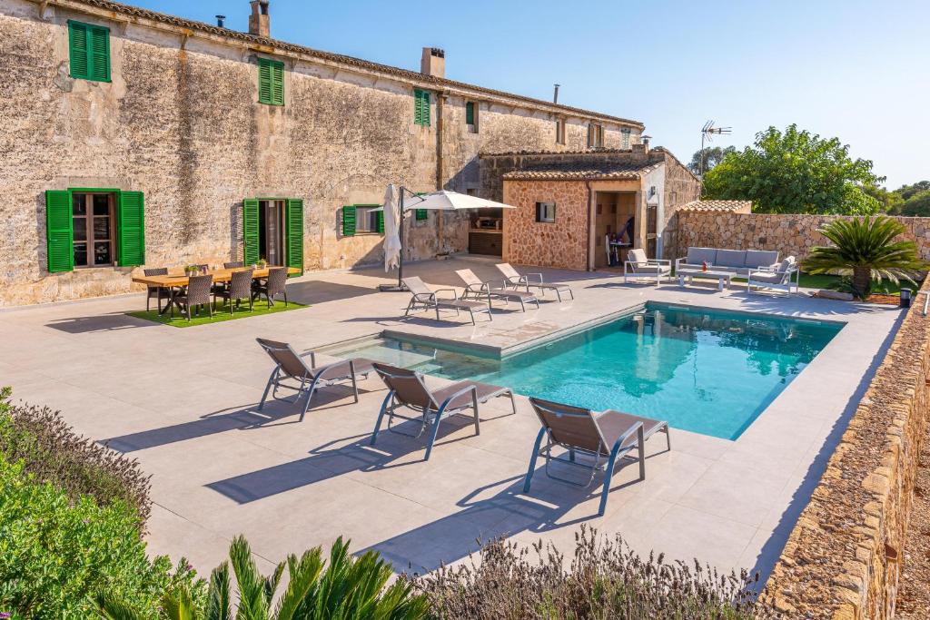 a pool with chairs and a table and a building at Son Veri Dalt in Llucmajor