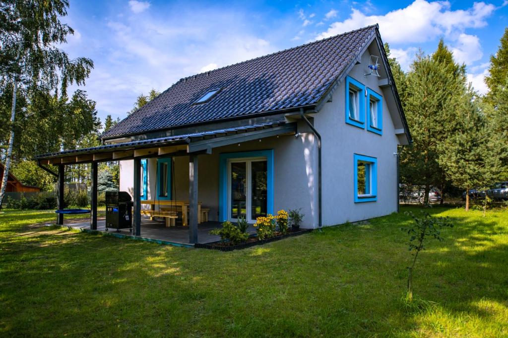 una pequeña casa con ventanas azules en un patio en Sea the Blue, en Odargowo
