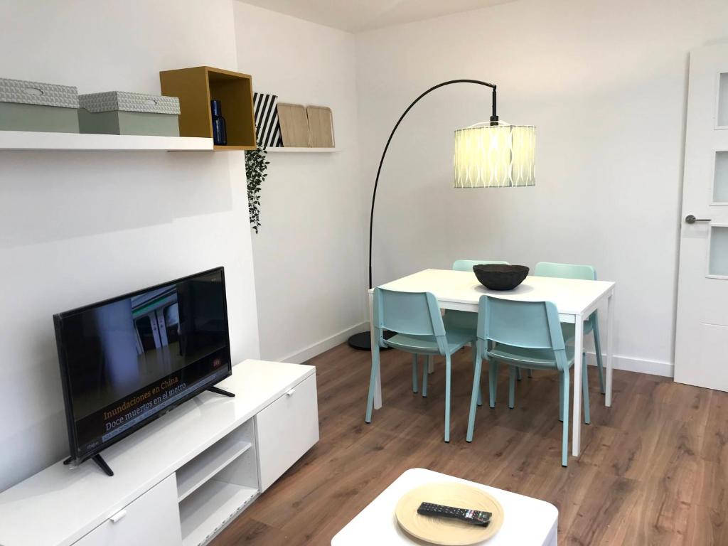 INSIDEHOME Apartments - La Casita de Úrsula في بالينثيا: غرفة معيشة مع طاولة مع كراسي وتلفزيون
