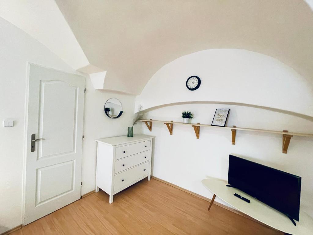 a room with a tv and a dresser and a door at Studio Nicolas II Prague in Prague