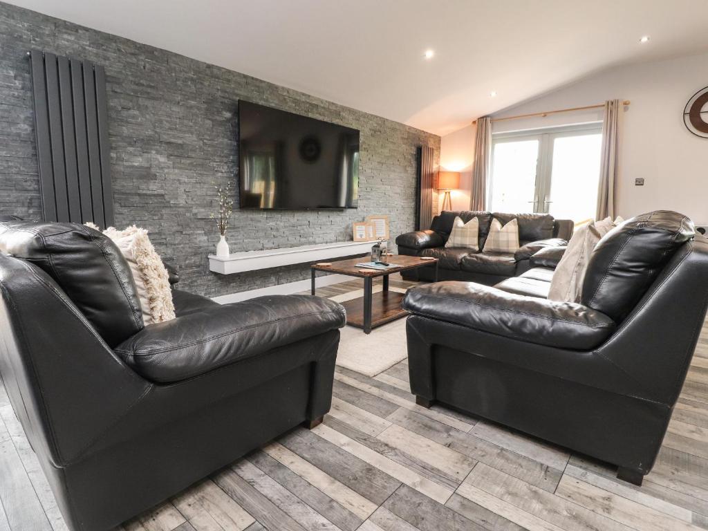 a living room with two leather chairs and a tv at Box Tree Escapes in Lancaster