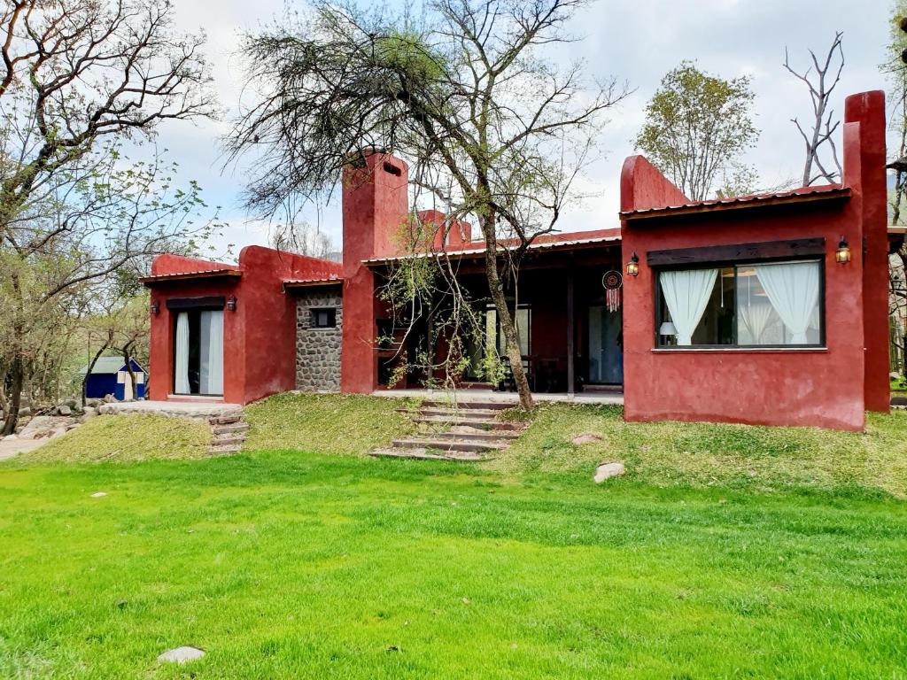 una casa roja con un césped verde delante de ella en RUNA Yaku en Salta