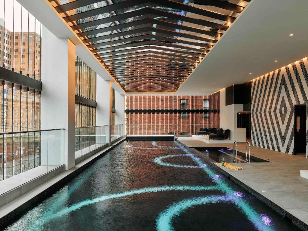 a lobby with a pool in the middle of a building at Movenpick Hotel Melbourne On Spencer in Melbourne