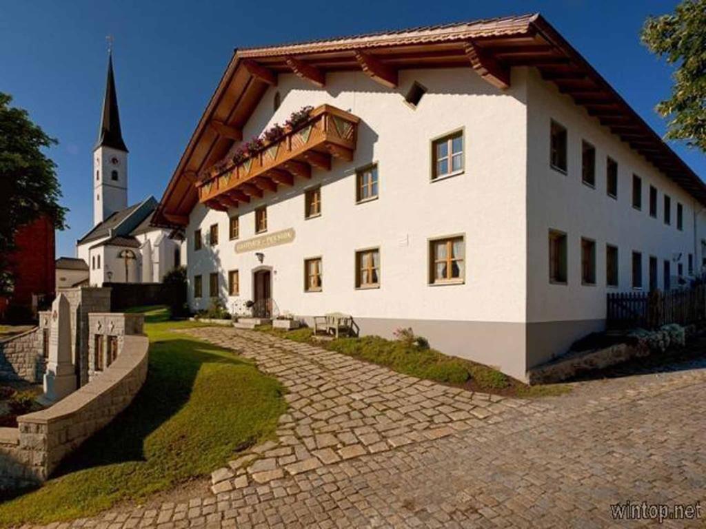 un grand bâtiment blanc avec une tour d'horloge en arrière-plan dans l'établissement Pension Zum Lebzelter, à Freyung
