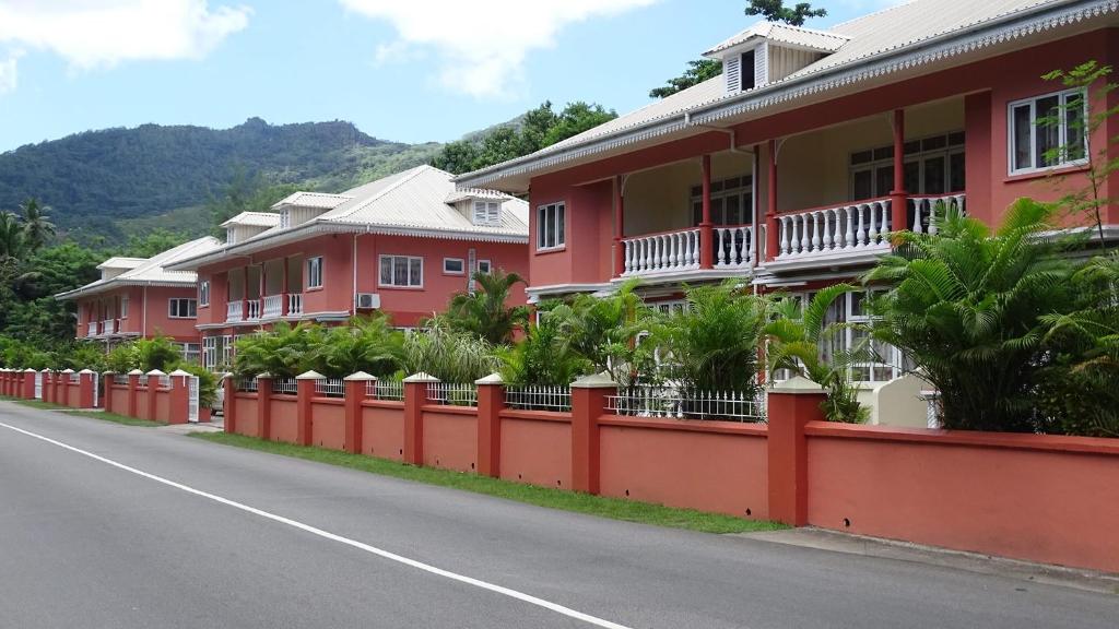 a row of red houses on the side of a road at Reef Holiday Apartments in Anse aux Pins