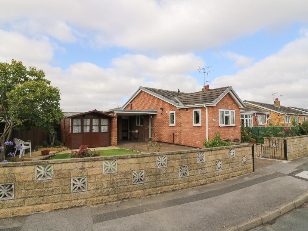 een stenen huis met een hek ervoor bij The Corner Bungalow in Great Driffield