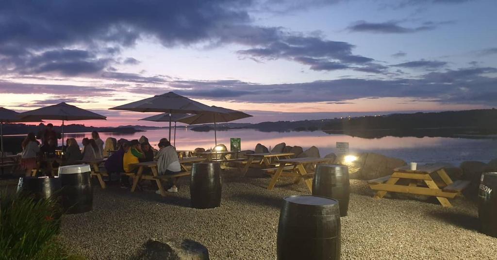 a group of people sitting at tables near a lake at Caisleain Oir Hotel in Annagry