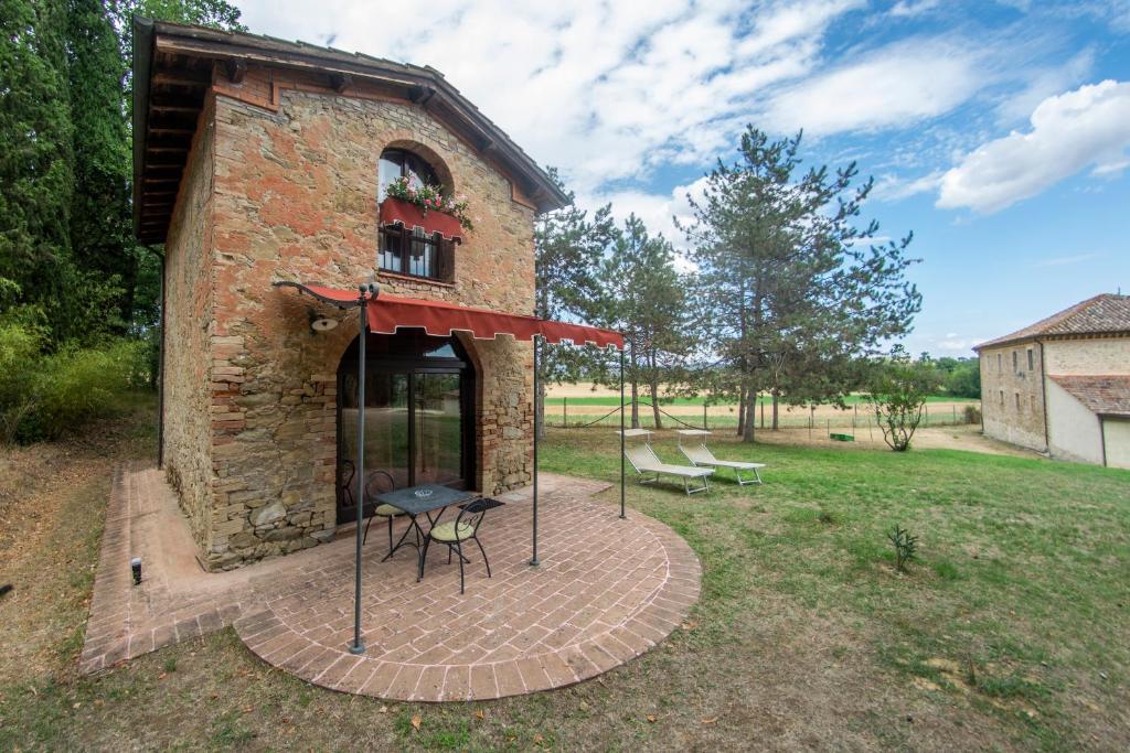 un edificio de ladrillo con una mesa y una parrilla en un patio en Agriturismo Poggiolo, en Pilonico Materno