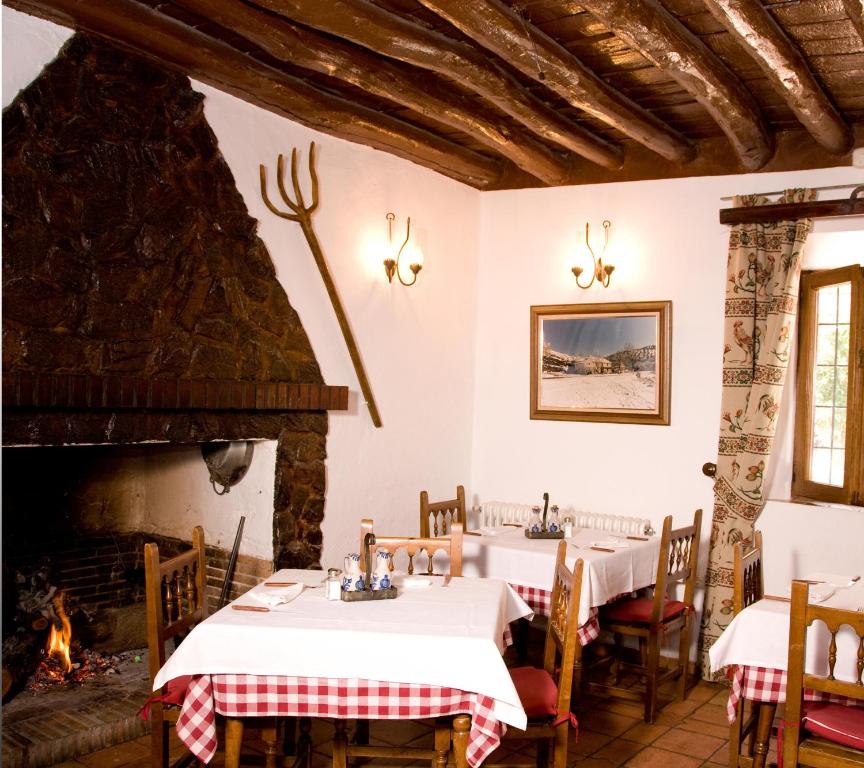 un restaurante con 2 mesas y una chimenea en El Ventorro Hospederia Rural, en Alhama de Granada
