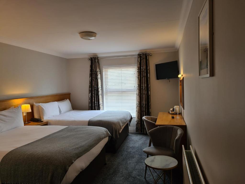 a hotel room with two beds and a desk at Caisleain Oir Hotel in Annagry