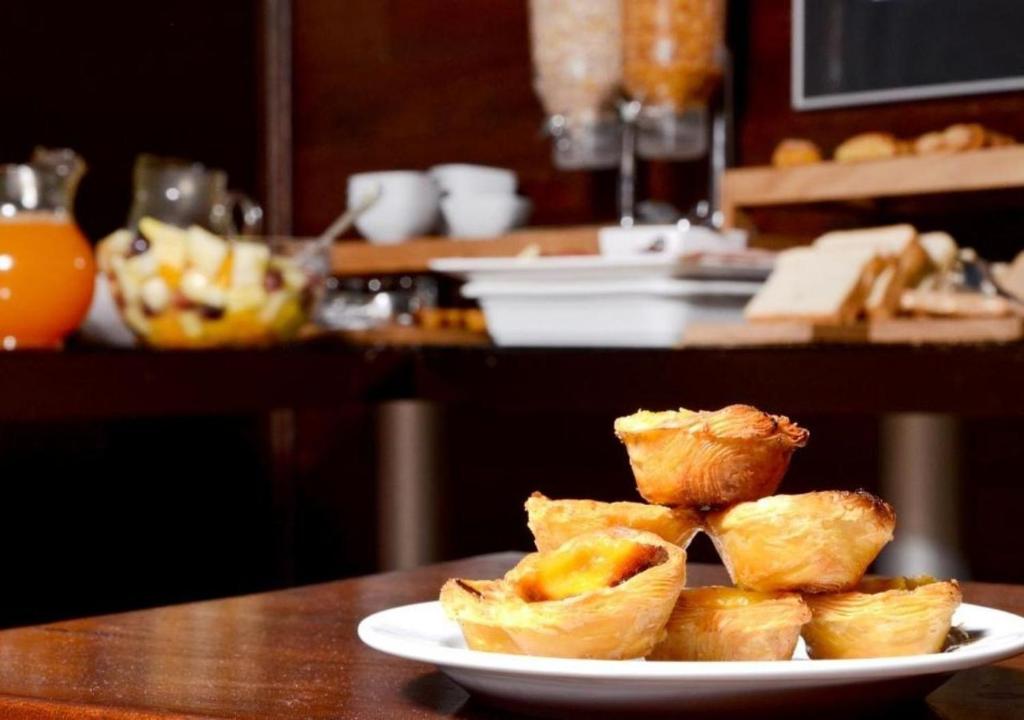 A plate of Portuguese-style custard tarts on a breakfast buffet.