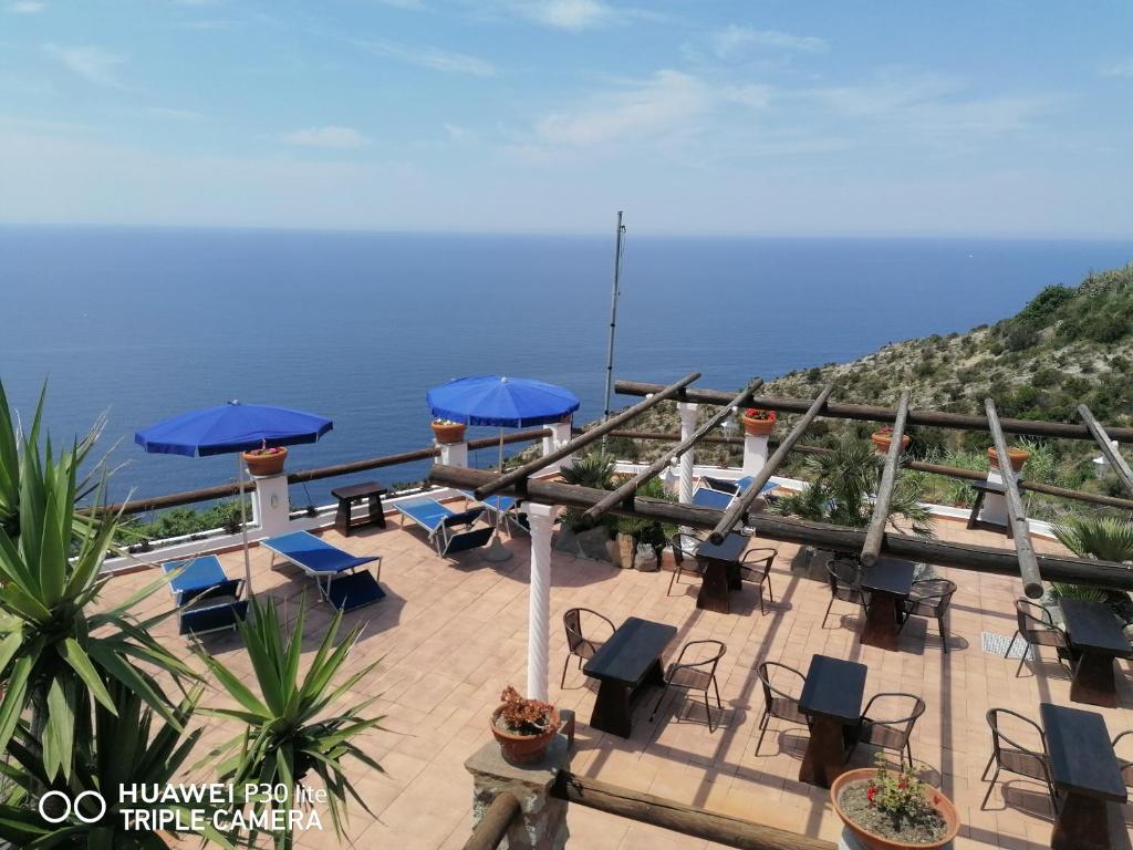 a patio with chairs and umbrellas and the ocean at Hotel Punto Azzurro in Ischia