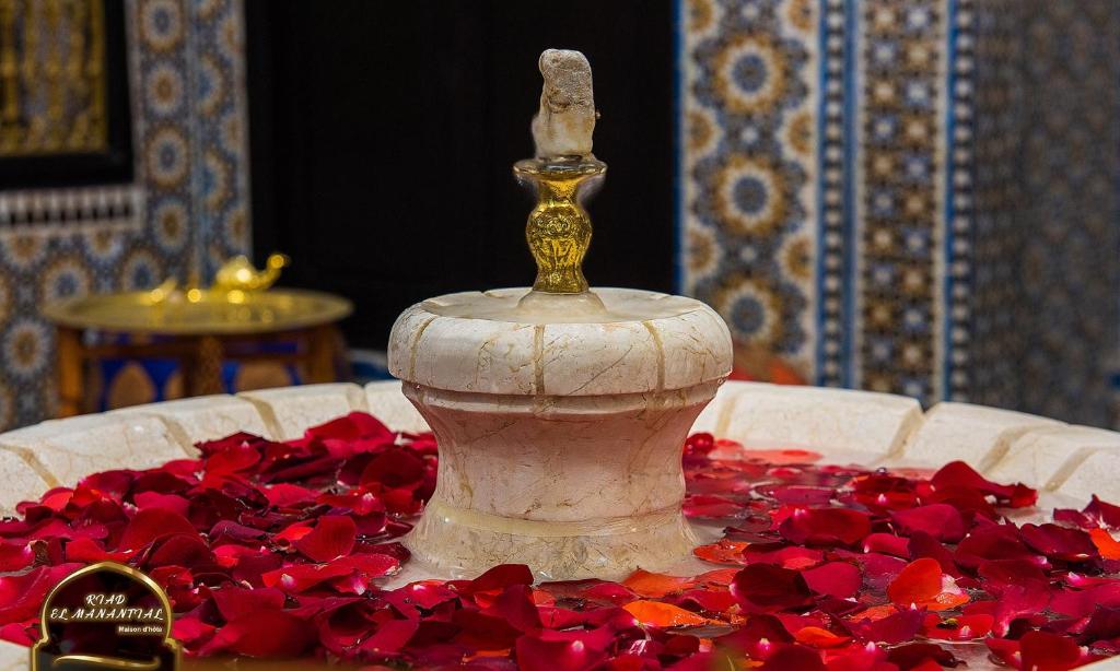 un vaso seduto su un tavolo con fiori rossi di Riad EL Manantial,Patrimonio del S XIX a Tétouan