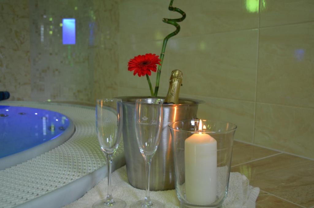 a candle and two wine glasses and a vase with a flower at Pokoje RELAX in Rybniště