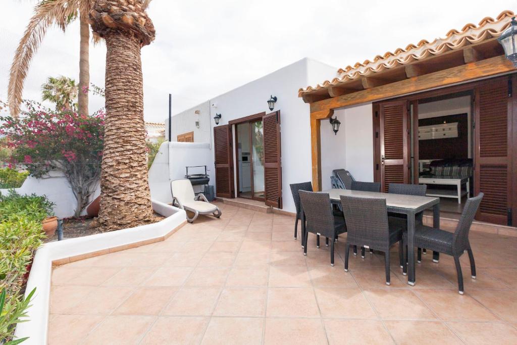 un patio con una mesa, sillas y una palmera en Harmony House, Golf del Sur, en San Miguel de Abona