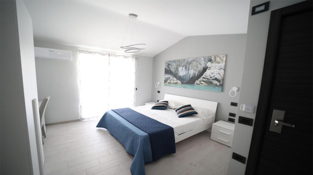 a white bedroom with a bed with a blue blanket at IsolaDino b&b sweet home in Praia a Mare