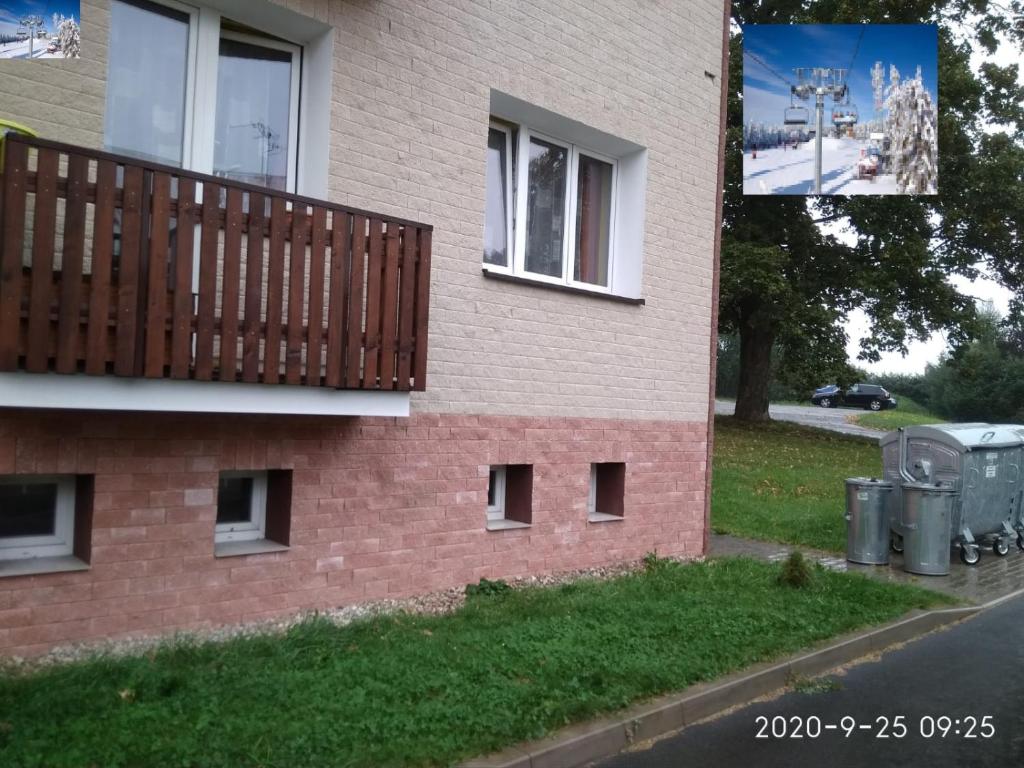 een bakstenen gebouw met een balkon en twee vuilnisbakken bij Plně vybavený 2+1byt s balkonem a kójí pro kola a lyže. in Rokytnice v Orlických Horách