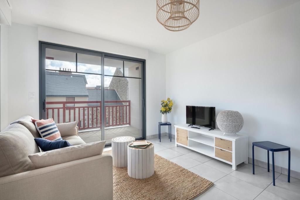 uma sala de estar com um sofá e uma televisão em Bel appartement pour 6 personnes avec balcon en bord de mer em Pléneuf-Val-André