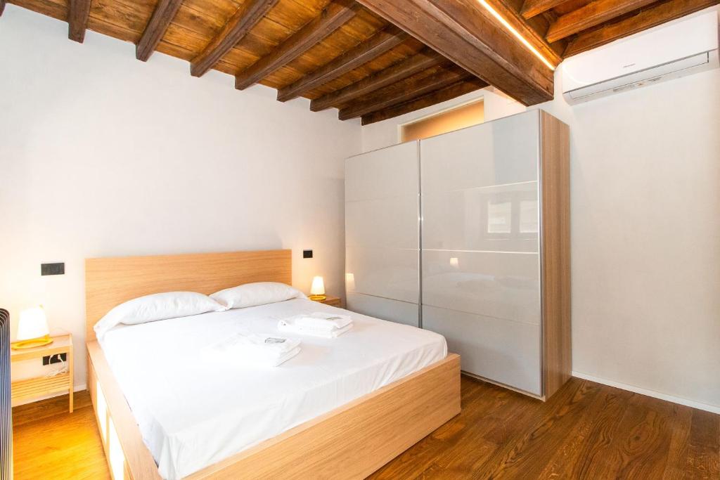 Schlafzimmer mit einem weißen Bett und einem Kühlschrank in der Unterkunft Stylish Quardilatero Romano Central Flat in Turin