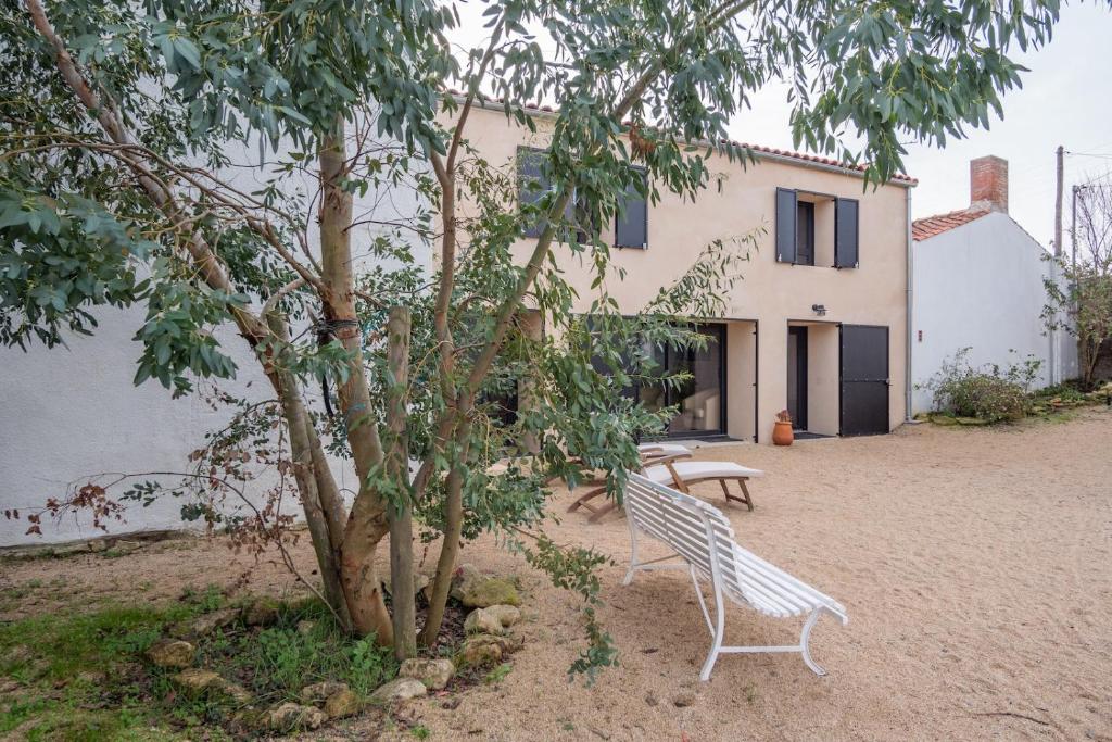 un banco blanco junto a un árbol delante de una casa en Maison de charme pour 6 personnes à Jard-Sur-Mer, en Jard-sur-Mer