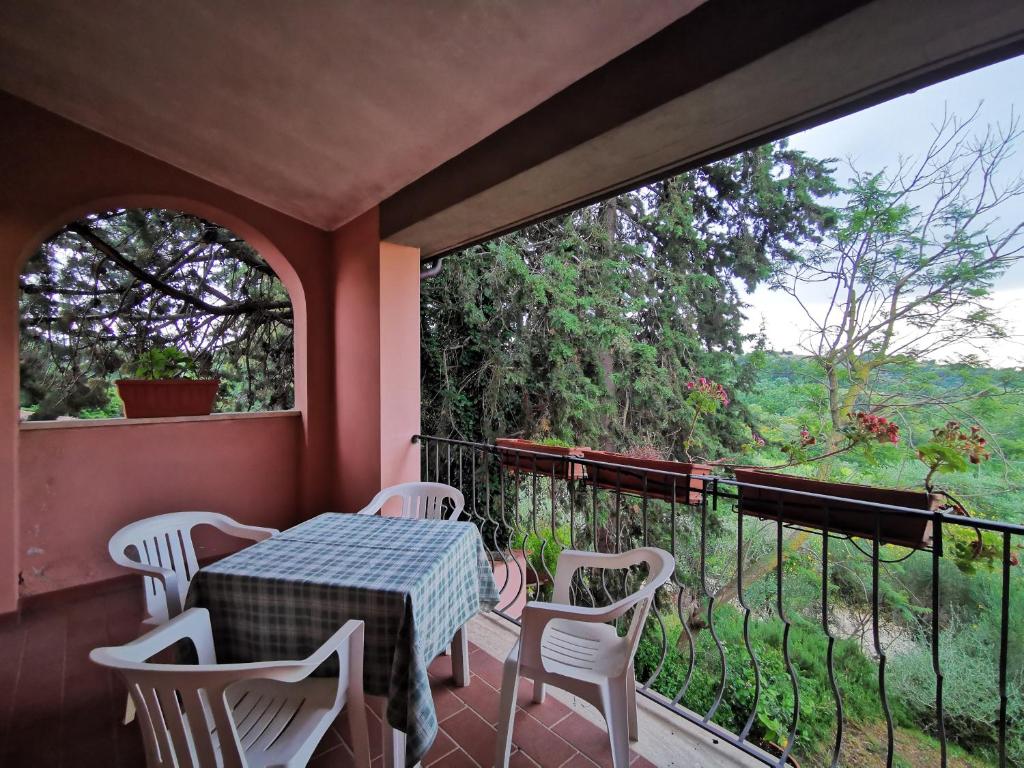 balcón con mesa, sillas y ventana en Il Melograno Country House, en Saturnia