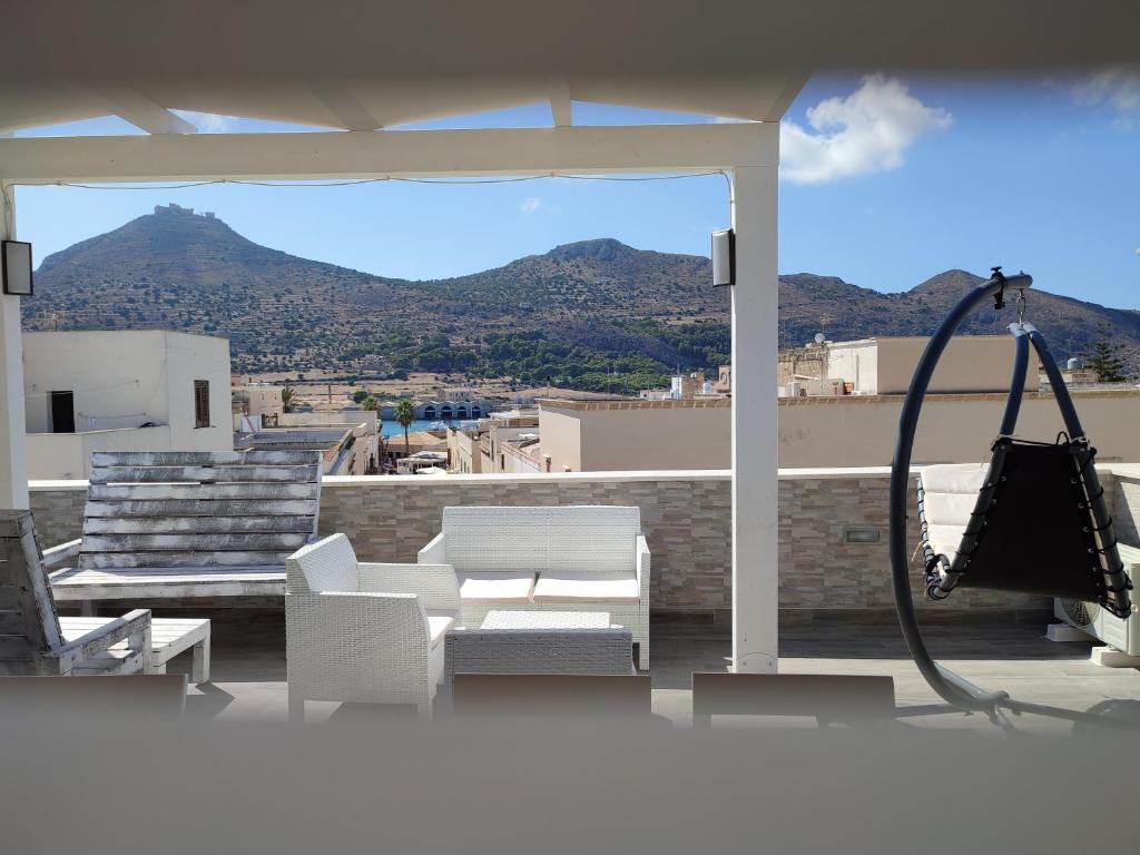 a patio with white furniture and a view of a mountain at Centralissima Favignana in Favignana