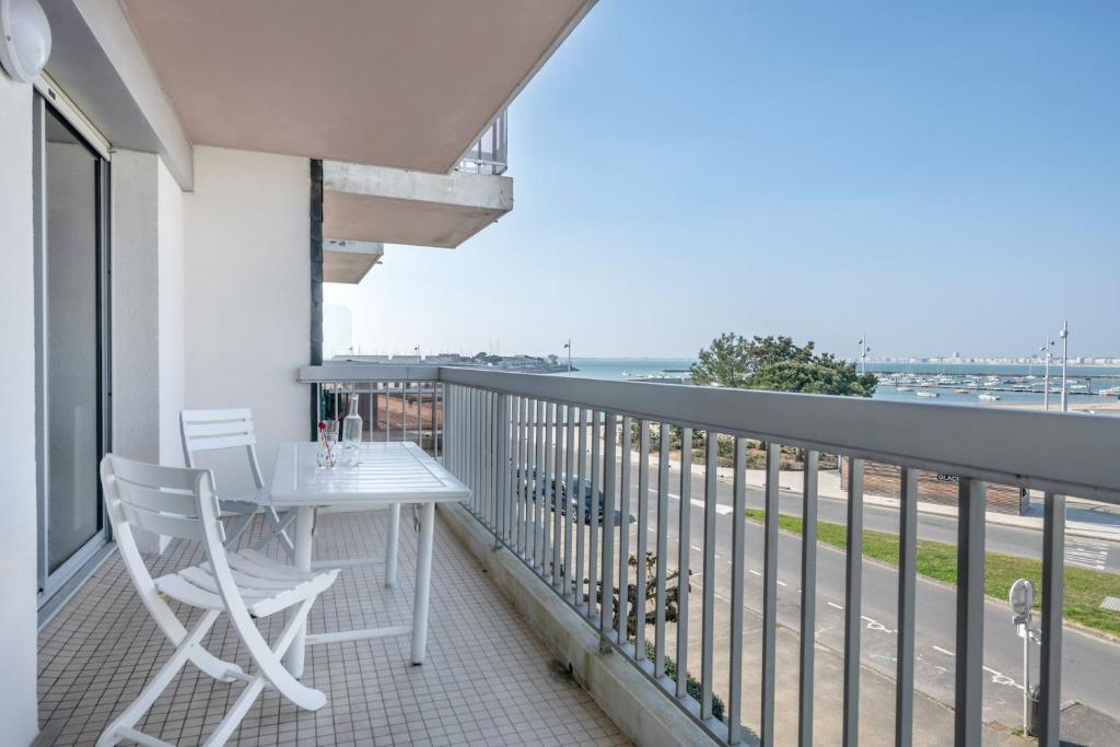 d'un balcon avec une table et des chaises blanches donnant sur l'océan. dans l'établissement Appartement pour 4 avec vue sur la marina, à Pornichet
