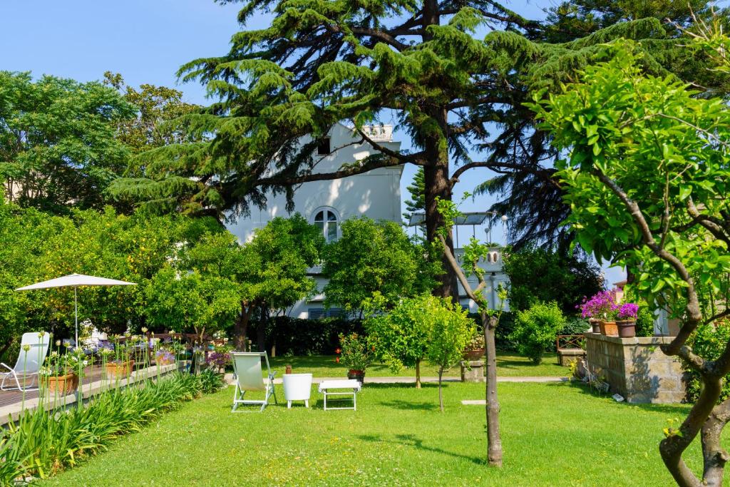 un parco con sedie, ombrellone e alberi di Villa Manning Relais a Sorrento