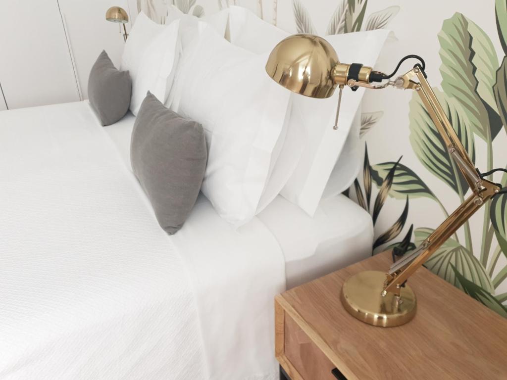 Vera Cruz Suite Apartment في أفيرو: سرير مع وسائد بيضاء ومكتب مع مصباح
