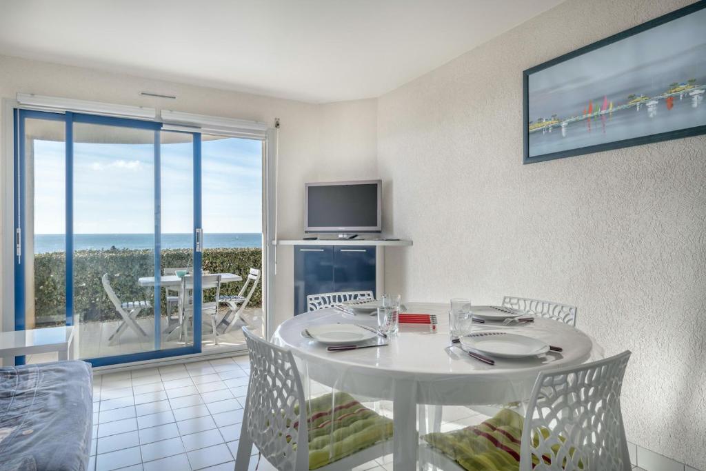 une salle à manger avec une table blanche et une télévision dans l'établissement À 200m de la plage, vue mer pour 4, au Croisic