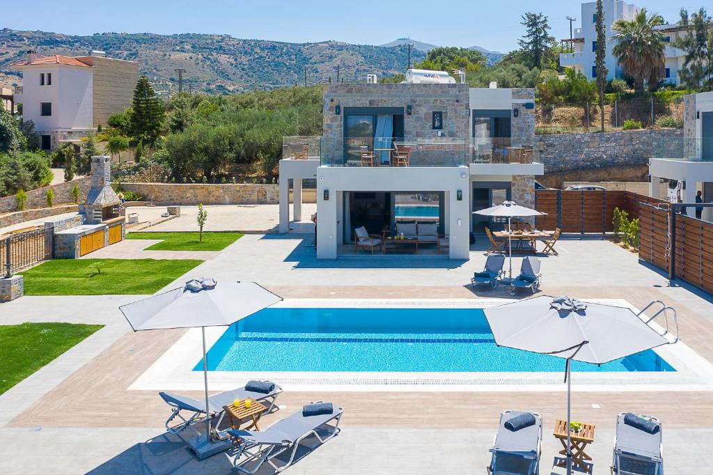 ein Pool mit Sonnenschirmen und ein Haus in der Unterkunft Olive and Sea Villas in Agia Pelagia