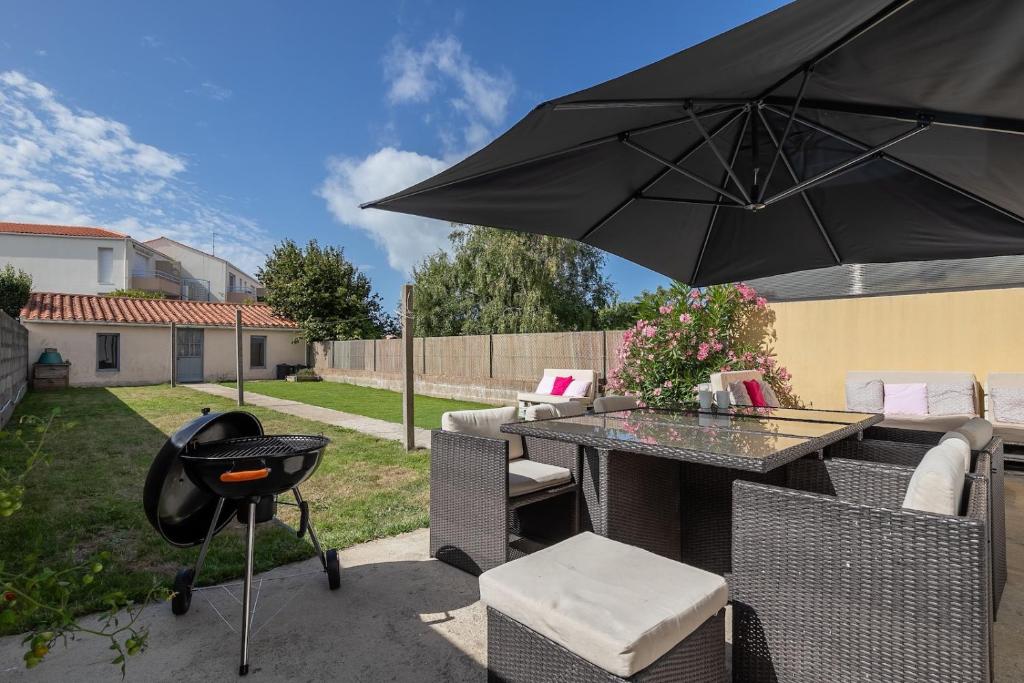 d'une terrasse avec un barbecue et un parasol noir. dans l'établissement Des vacances en bord de mer pour 10 personnes, à Château-dʼOlonne