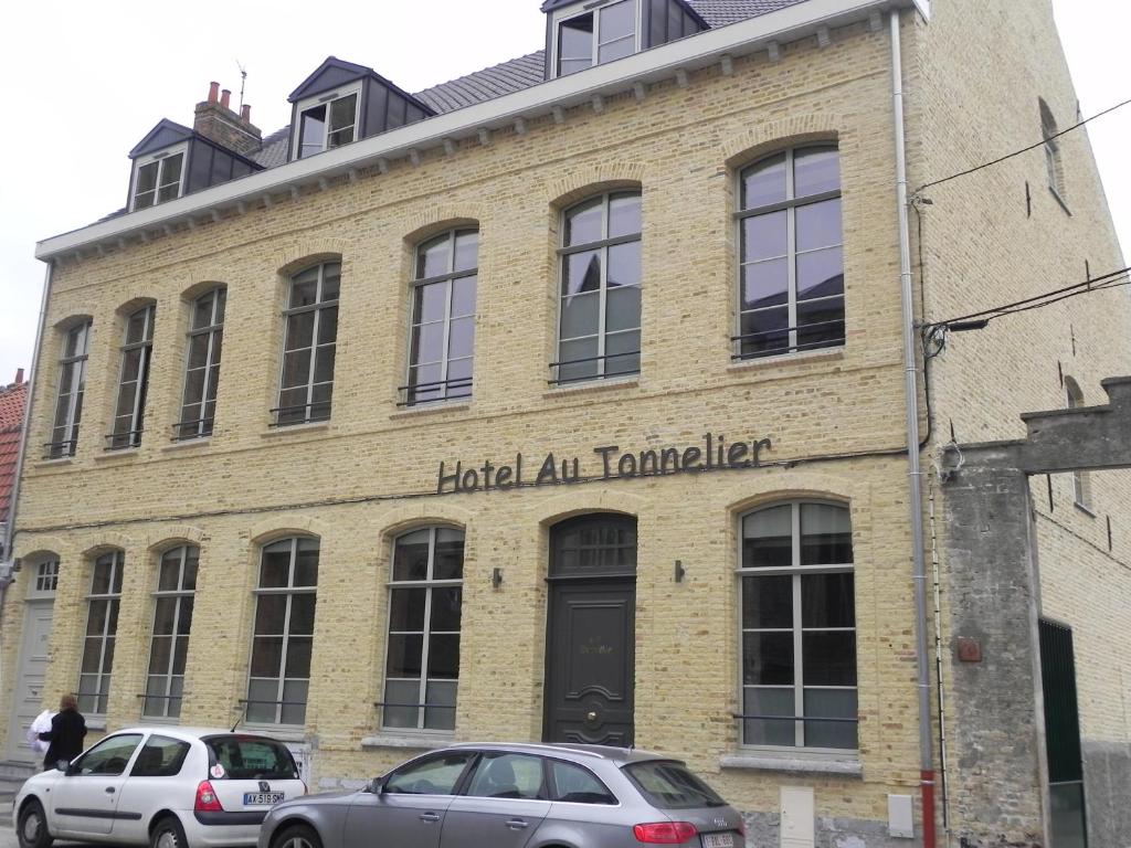 twee auto's geparkeerd voor een bakstenen gebouw bij Hôtel - Restaurant Au Tonnelier in Bergues