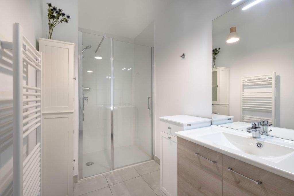 a white bathroom with a shower and a sink at Charmant appartement sur le remblai de Pleneuf Val Andre in Pléneuf-Val-André