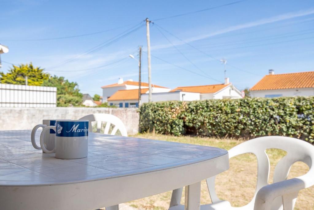 - une tasse de café assise sur une table avec des chaises dans l'établissement Agréable maison pour 6 à Saint-Hilaire-de-Riez, à Saint-Hilaire-de-Riez