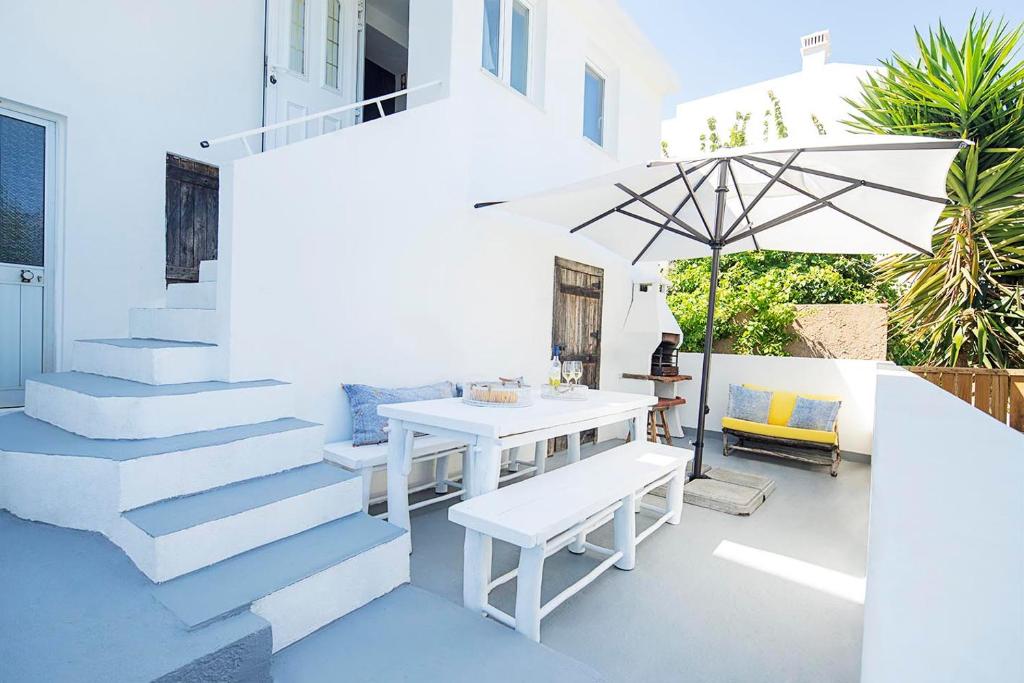 a white patio with a table and an umbrella at Casa Cavala by Sevencollection in Salema