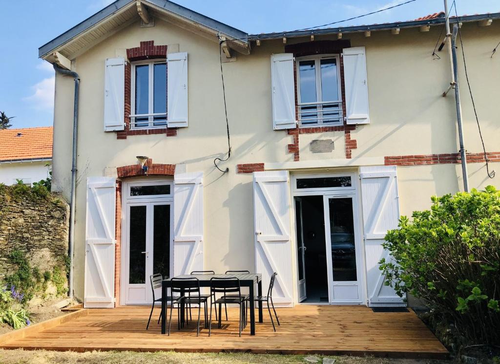 uma casa com cadeiras e mesas num deque de madeira em Maison avec terrasse à 50 m de la mer em Pornic