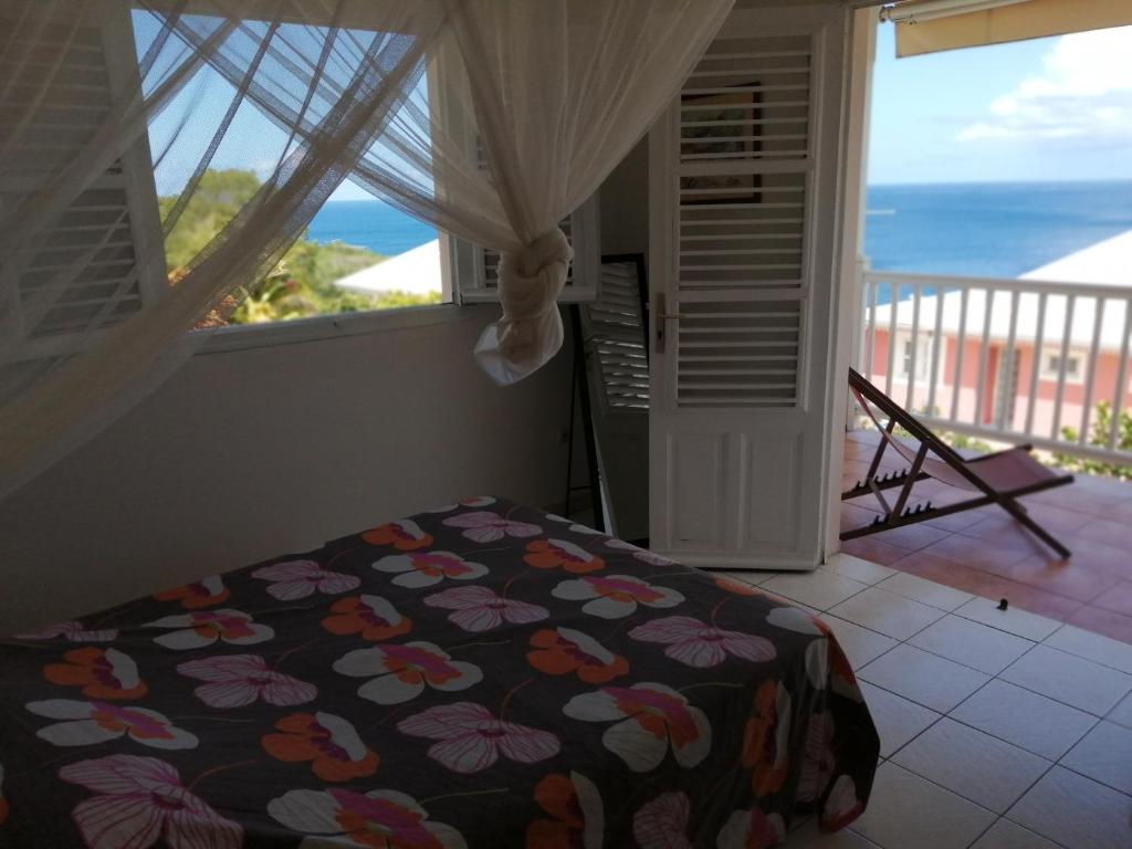 Schlafzimmer mit einem Bett und Meerblick in der Unterkunft Rose phoenix appartement terrasse et piscine vue mer in Les Anses-dʼArlets