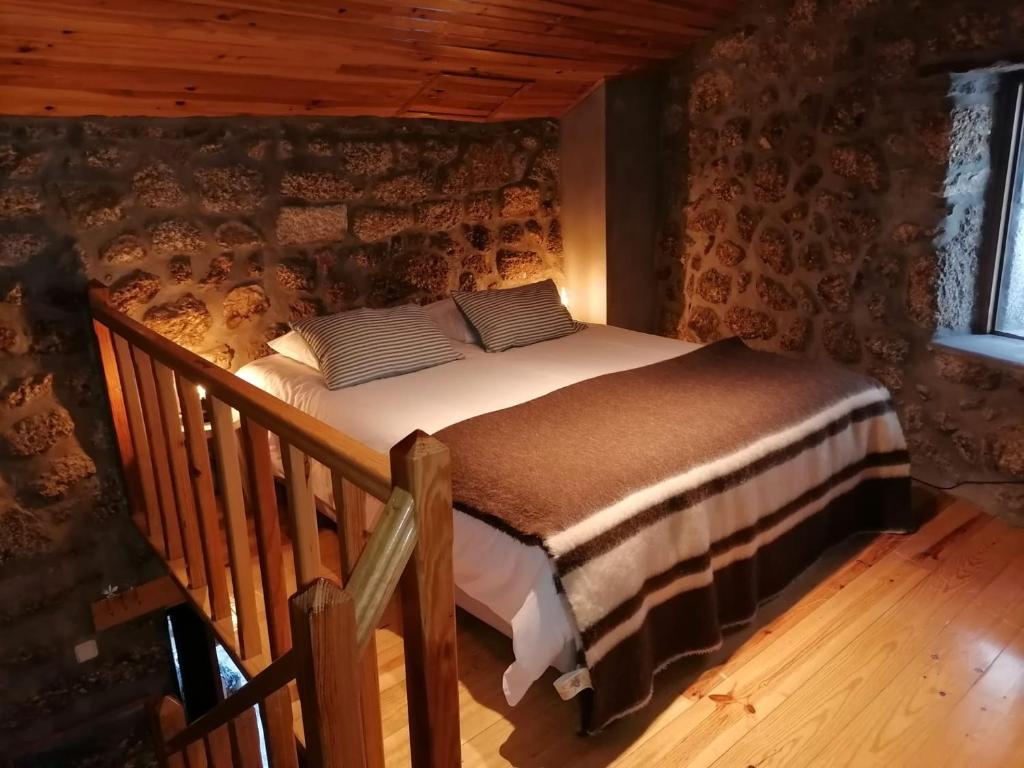 um quarto com uma cama num chalé de madeira em Casa Encantada - Alvoco da Serra em Alvoco da Serra
