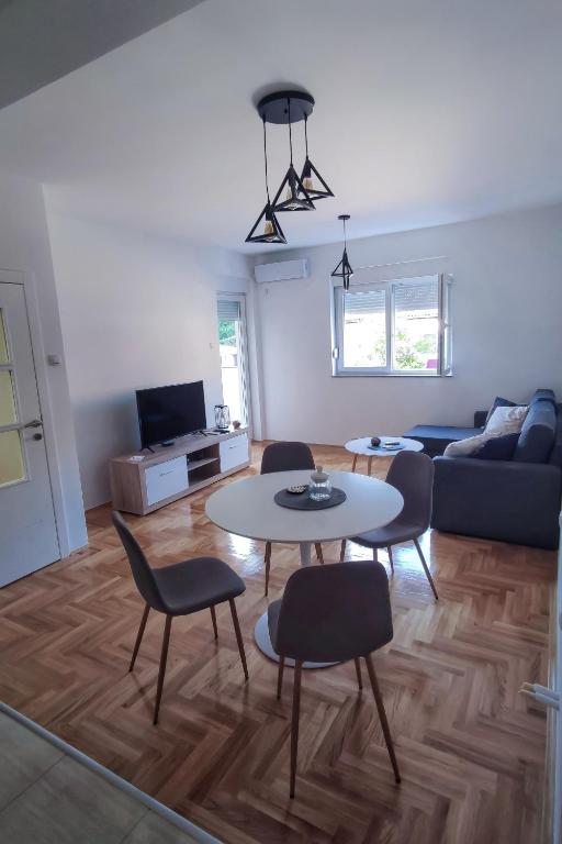 un soggiorno con tavolo, sedie e divano di Apartman Vuković a Trebinje